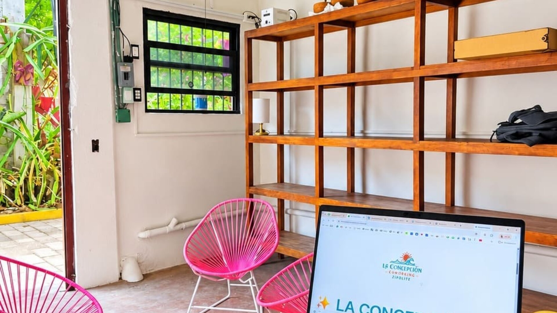 Espacio de coworking luminoso con sillas de colores y vistas a la vegetación tropical